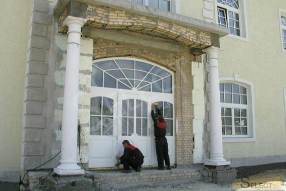 Works on the facade of the cottage. Installation of the central door.